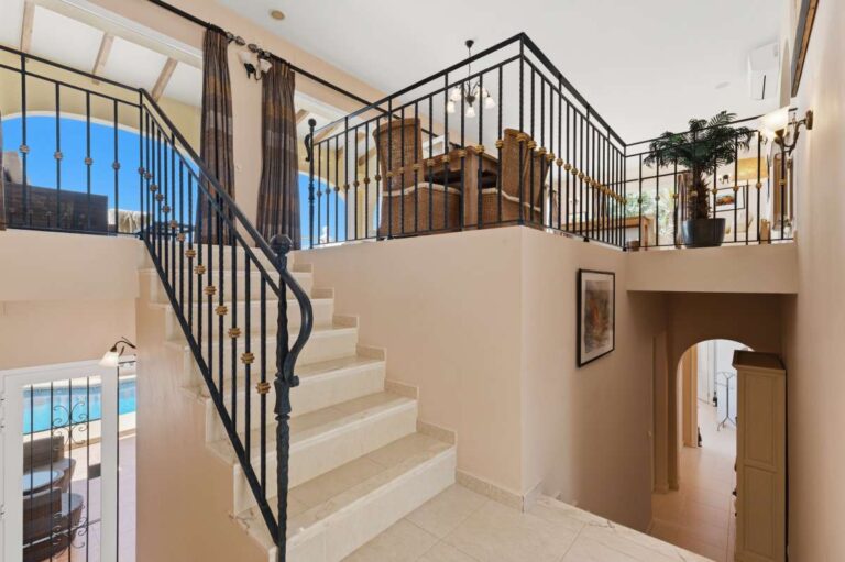 Interior staircase inside an elegant Mediterranean villa in Altea Hills with black railings, split-level layout and bright hallway space