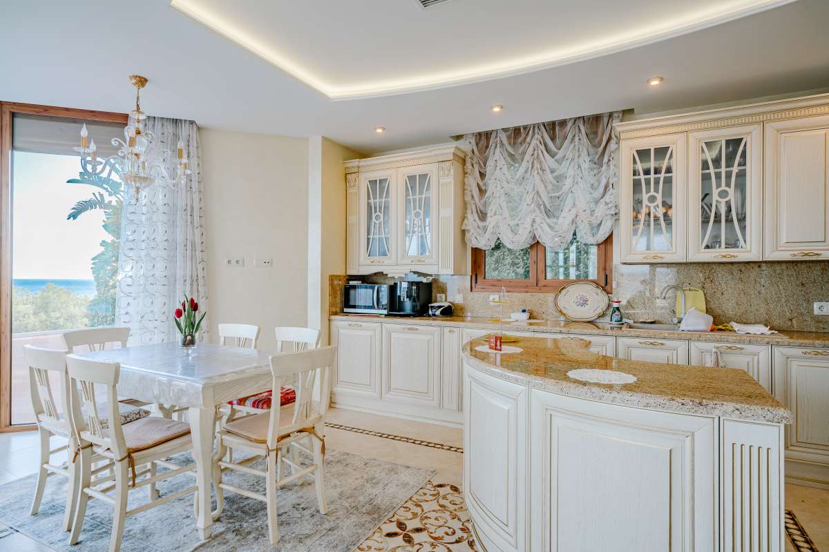 Kitchen and breakfast area with traditional cabinetry and natural light inside a frontline villa in Les Bassetes.