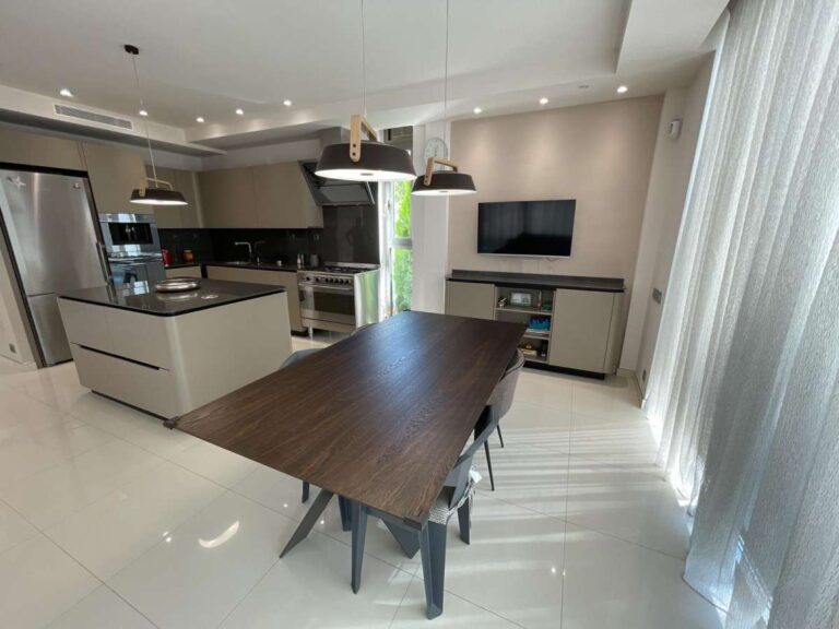 Kitchen and dining area inside a modern luxury villa in La Calalga, Calpe with central island, dining table and large windows