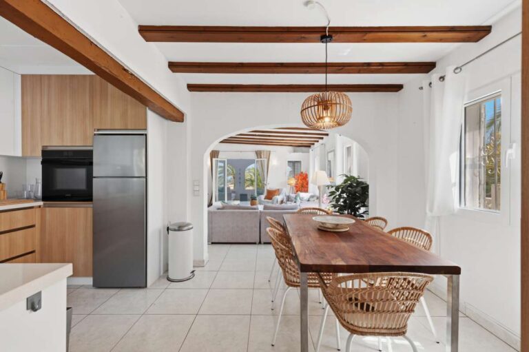 Kitchen and dining area inside a renovated single-level villa in Moraira with exposed beams, wooden dining table and open-plan layout