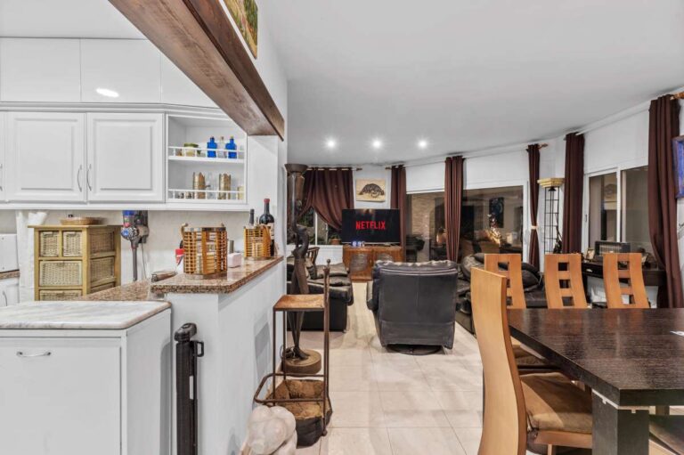 Kitchen and dining area inside an independent level of a Benissa sea view villa with white cabinetry, dining table and open living space
