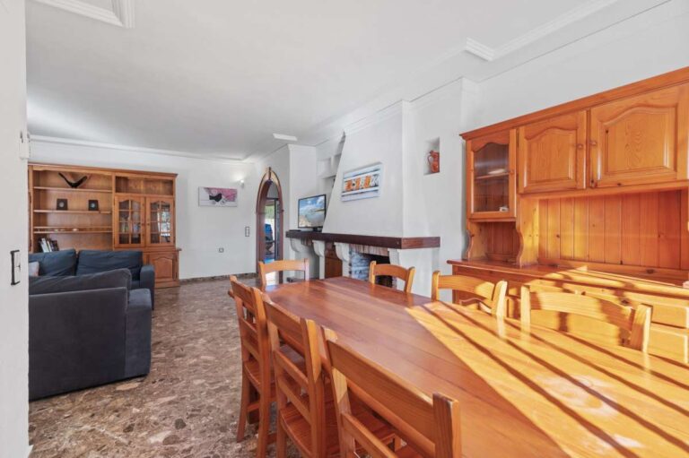 Kitchen and dining area with wooden finishes and open connection to the living space inside a spacious villa in Calpe.