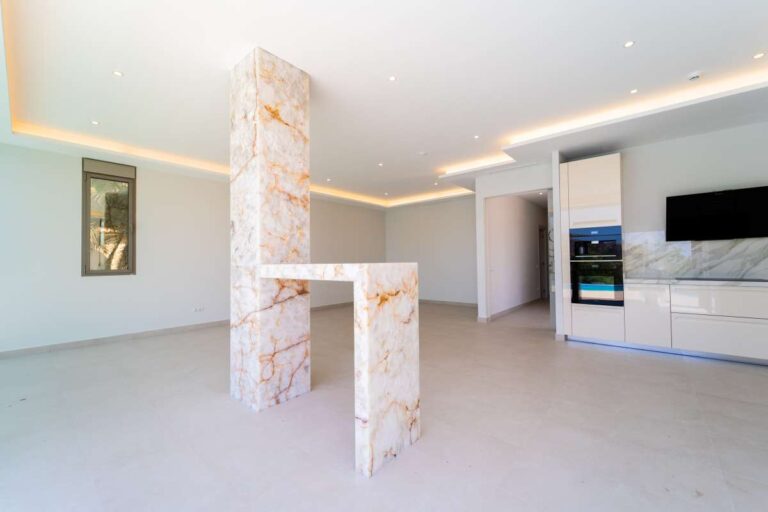 Küche und Wohnbereich in einer neu gebauten Luxusvilla in der Nähe des Yachthafens Puerto Blanco in Calpe mit steinerner Säule, moderner Kochinsel und offenem Grundriss