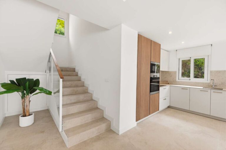 Kitchen and staircase area inside a modern villa in Altea Hills with integrated appliances, neutral finishes and bright open layout