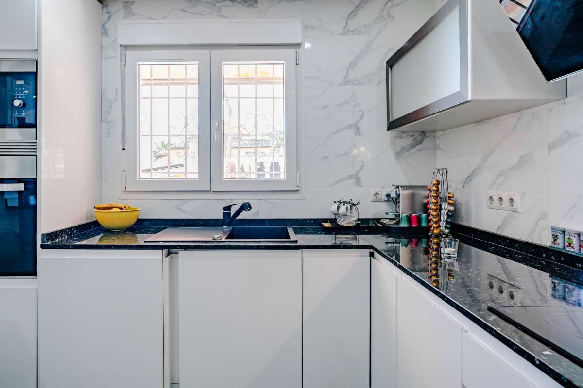 Kitchen detail with fitted cabinets, window and modern appliances inside a renovated Mediterranean villa in La Cometa, Calpe.