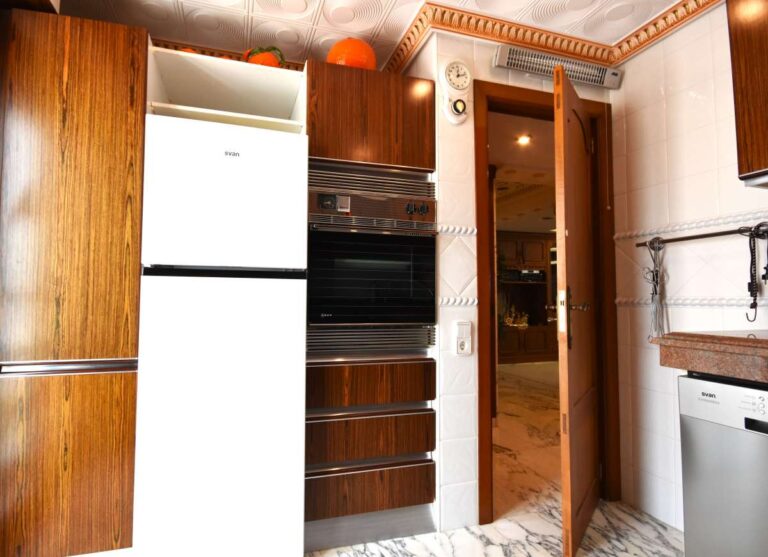Kitchen detail with wooden cabinetry and integrated appliances inside a frontline double penthouse on Arenal Beach in Calpe.