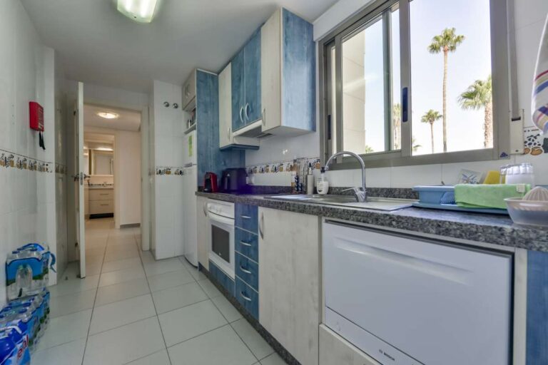 Kitchen inside a frontline La Fossa apartment in Calpe with fitted cabinets, appliances and natural light from the window