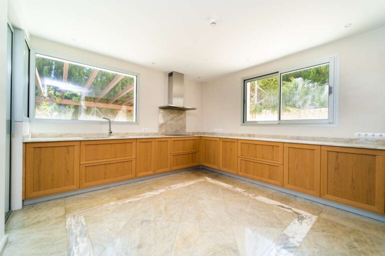 Kitchen inside a luxury villa in Calpe with wood cabinetry, marble flooring, large windows and spacious worktop area
