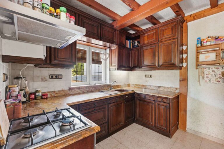 Kitchen inside a Mediterranean villa in Benissa Costa with wooden cabinets, tiled worktops, gas hob and exposed ceiling beams