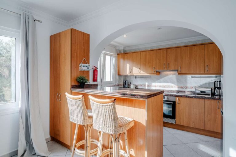 Kitchen inside a villa in Calpe with wooden cabinetry, breakfast bar and natural light
