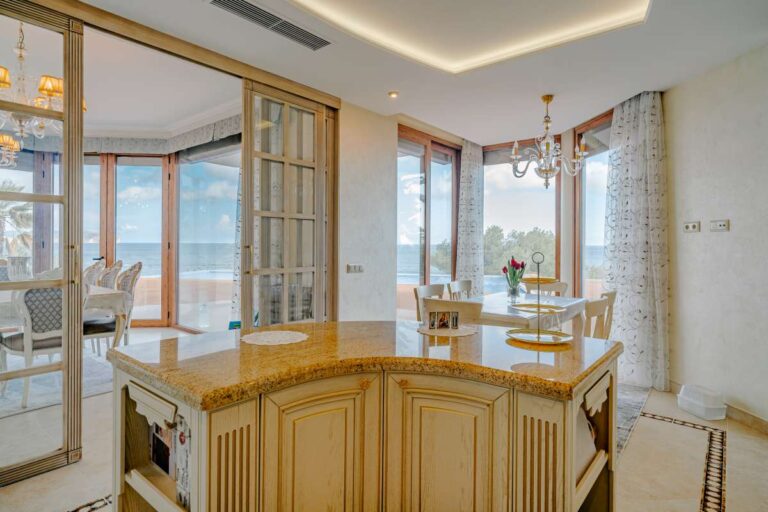 Kitchen island and dining area with sea views inside a frontline villa in Les Bassetes, Benissa Coast.