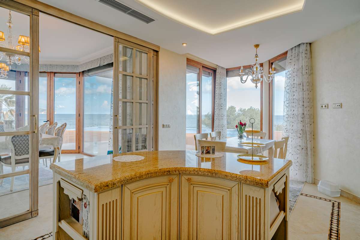 Kitchen island and dining area with sea views inside a frontline villa in Les Bassetes, Benissa Coast.