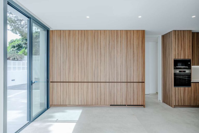 Kitchen storage area inside a modern villa in La Calalga, Calpe with wood cabinetry, built-in appliances and terrace access