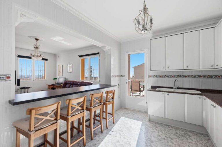 Kitchen with breakfast bar, fitted cabinets, and natural light inside a villa in Calpe.