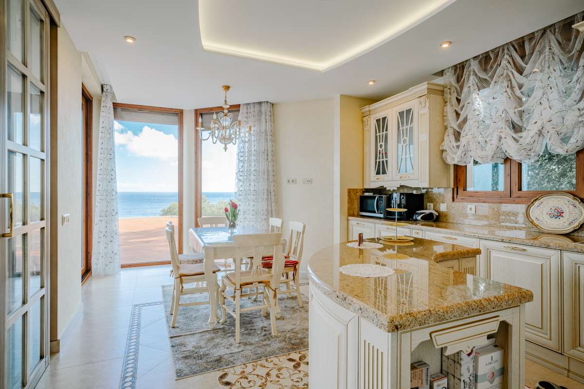 Kitchen with dining area, large windows and sea views inside a frontline villa in Les Bassetes, Benissa Coast.