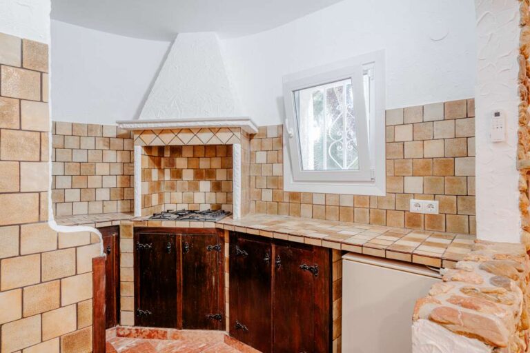 Kitchen with tiled walls and wooden cabinets inside an independent apartment at a Mediterranean villa in Maryvilla, Calpe.