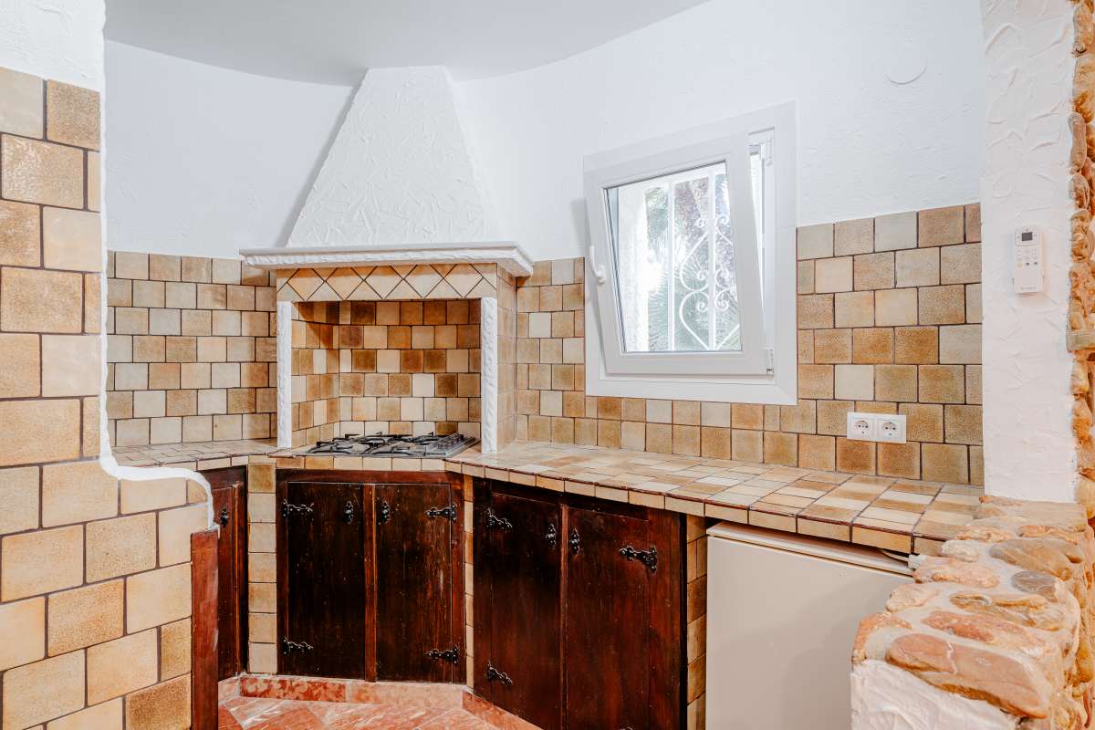 Kitchen with tiled walls and wooden cabinets inside an independent apartment at a Mediterranean villa in Maryvilla, Calpe.