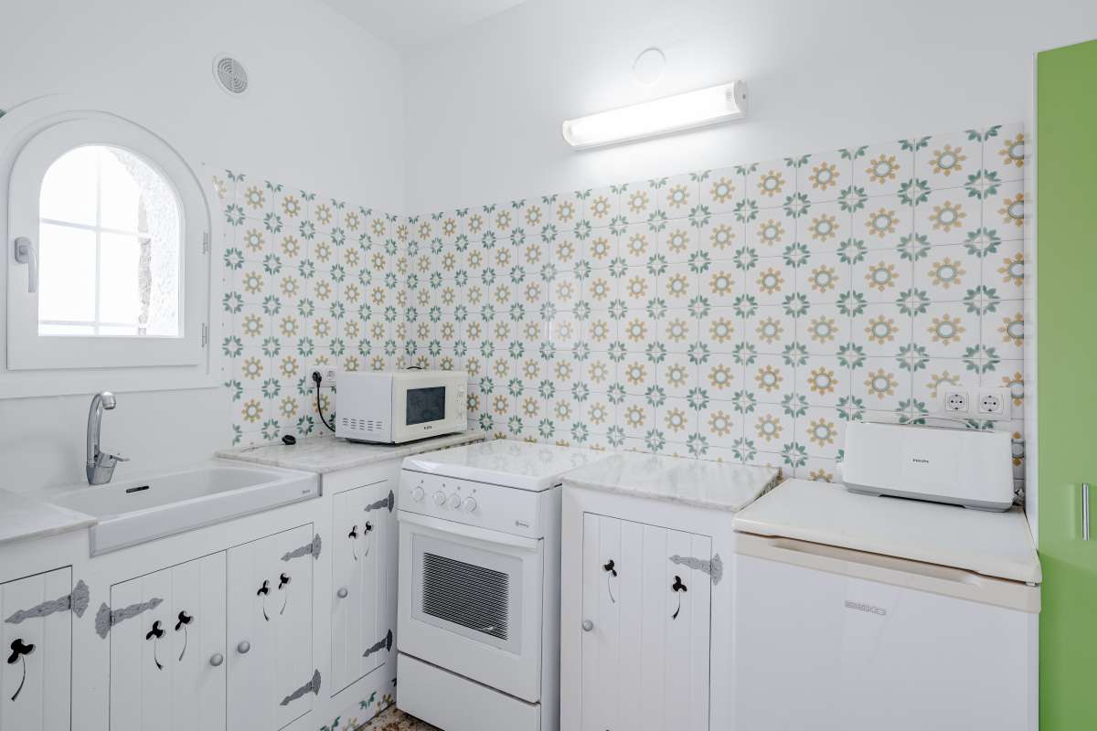 Kitchen with white cabinetry, arched window and patterned tiles inside an independent apartment at a Mediterranean villa in Maryvilla, Calpe.