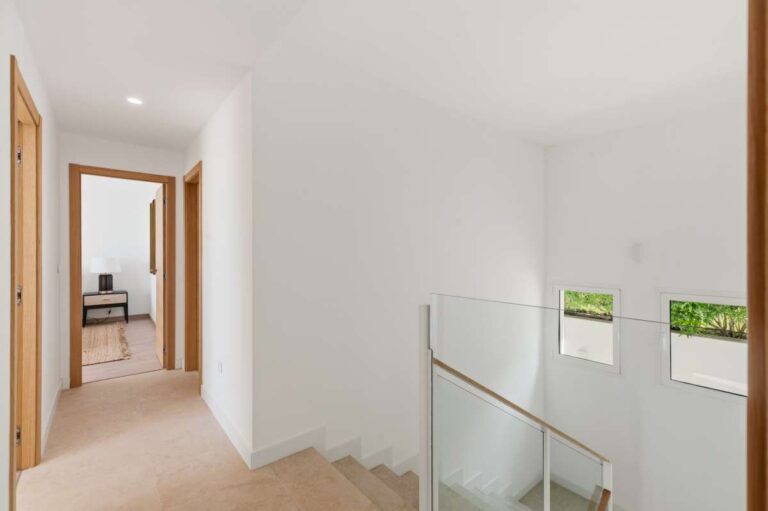 Landing inside a modern villa in Altea Hills with staircase access, glass railing, bedroom access and bright neutral interior