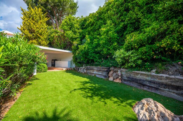 Landscaped garden at a modern villa in Altea Hills with lawn, stone retaining wall, mature greenery and peaceful outdoor space