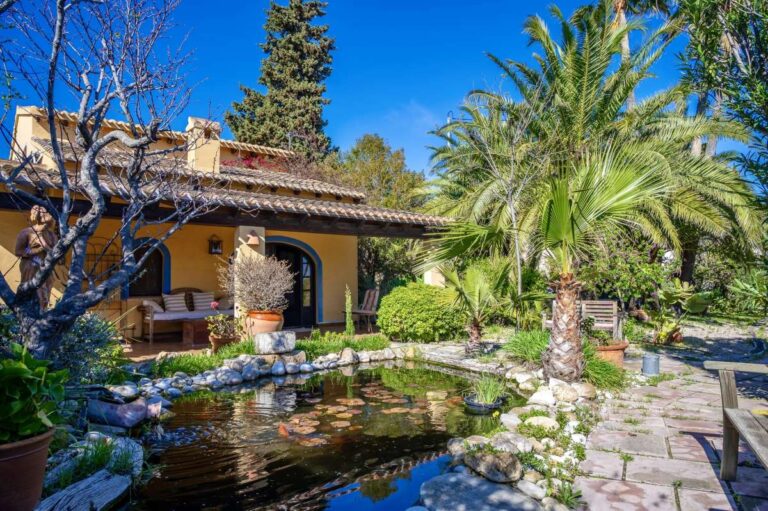 Landscaped garden at a traditional Spanish finca near Moraira with pond, stone pathways, palm trees and mature Mediterranean planting