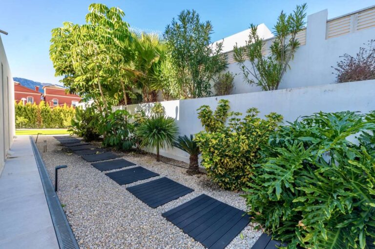Landscaped garden pathway with tropical planting and privacy walls at a modern oasis villa near Arenal-Bol Beach in Calpe.