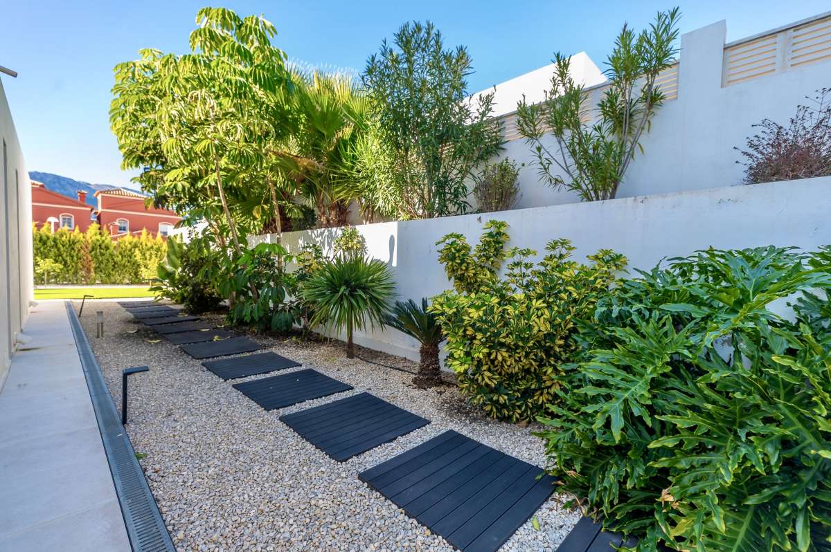 Landscaped garden pathway with tropical planting and privacy walls at a modern oasis villa near Arenal-Bol Beach in Calpe.