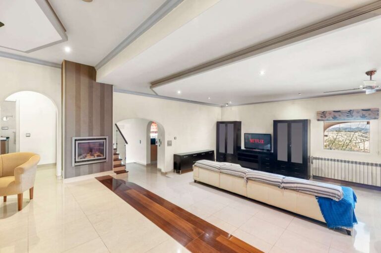 Large double-height living room inside a private villa in Calpe with fireplace, staircase, TV area and natural light