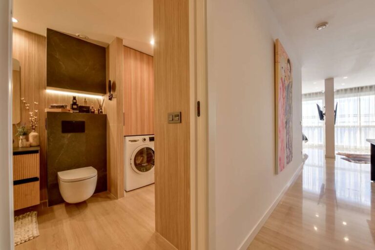 Laundry and guest toilet area inside a luxury frontline beach duplex in Mascarat, Altea with washing machine, toilet, sink and modern lighting
