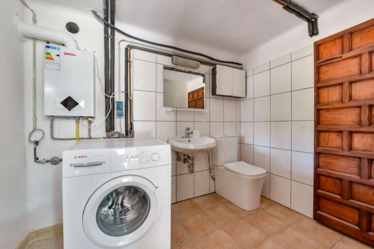 Laundry room and guest WC inside a charming Benissa Coast villa with washing machine, sink, toilet and tiled walls