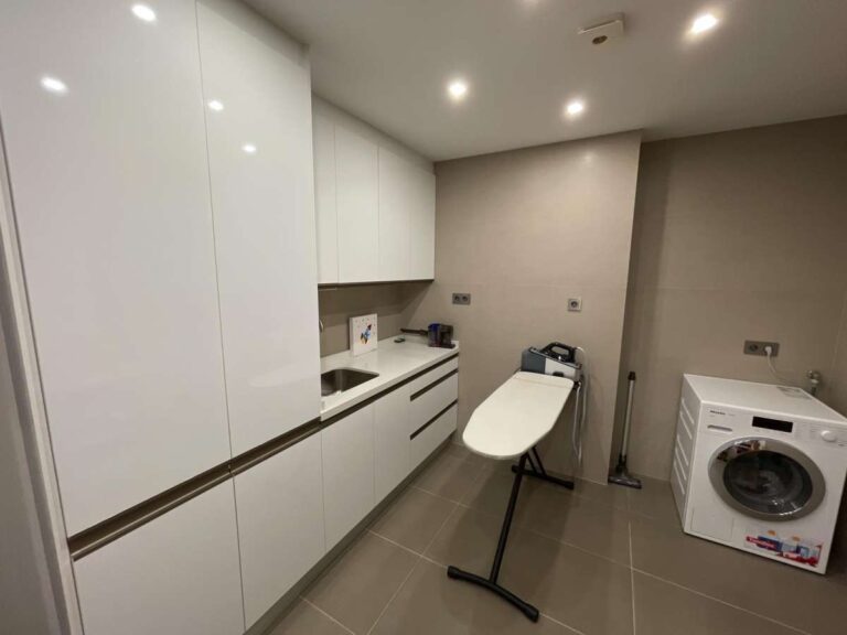 Laundry room inside a modern luxury villa in La Calalga, Calpe with fitted cabinets, washing machine, ironing area and storage space