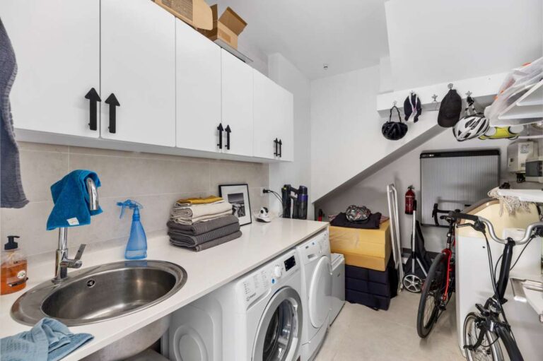 Laundry room with washing machine, storage cabinets and utility space inside a modern oasis villa in Calpe.