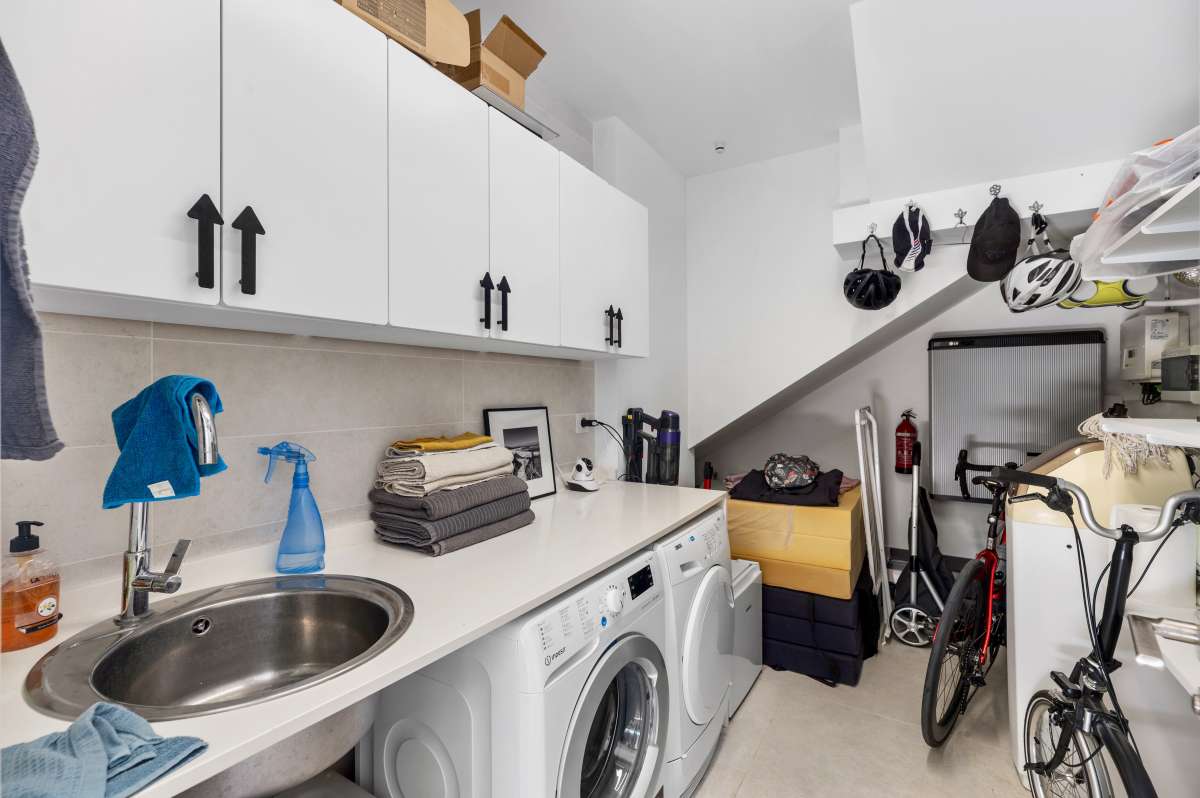 Laundry room with washing machine, storage cabinets and utility space inside a modern oasis villa in Calpe.