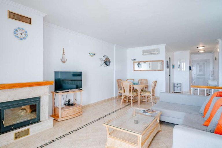 Living and dining area inside a duplex apartment near Les Platgetes Beach in Moraira with fireplace, sofa seating, dining table and bright interior