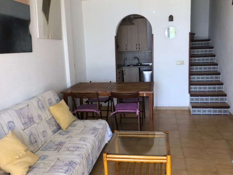 Living and dining area inside a frontline townhouse in Calpe with staircase and integrated kitchen area