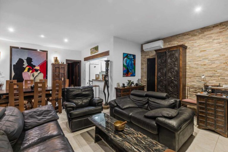 Living and dining area inside an independent level of a Benissa villa with leather seating, stone feature wall and dining table