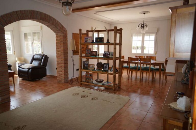 Living and dining area with arched opening and traditional furniture inside a Mediterranean villa in Calpe.