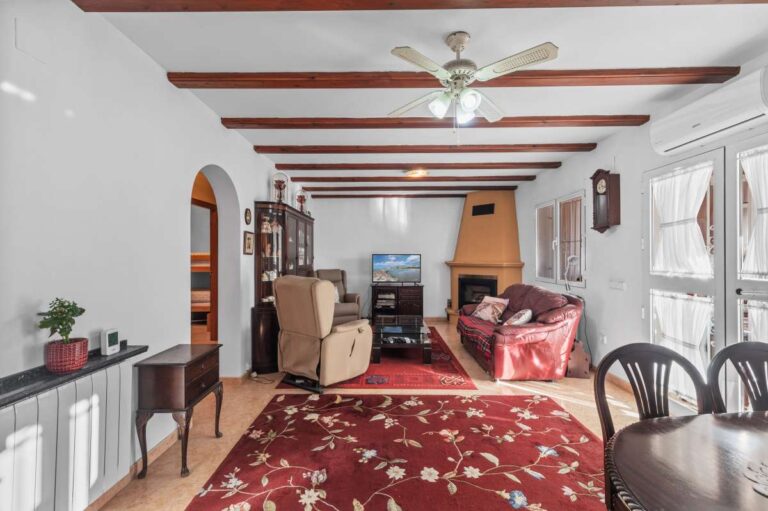Living and dining area with fireplace and exposed ceiling beams inside a south-facing single-level villa in Calpe.