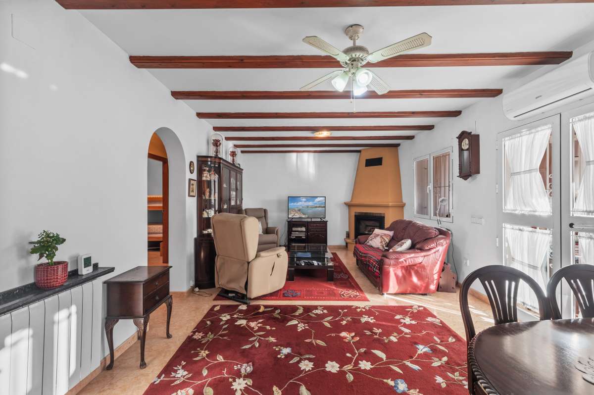 Living and dining area with fireplace and exposed ceiling beams inside a south-facing single-level villa in Calpe.