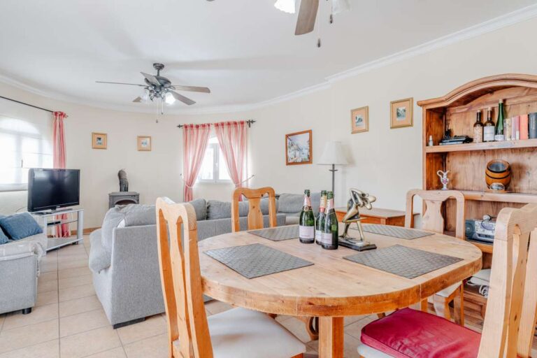 Living and dining area with fireplace, ceiling fans and traditional furniture inside a Mediterranean villa with independent guest accommodation in Calpe.