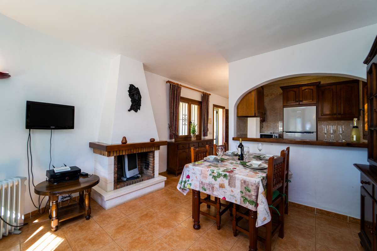 Living and dining area with fireplace, open kitchen and natural light inside a Mediterranean villa in Calpe.