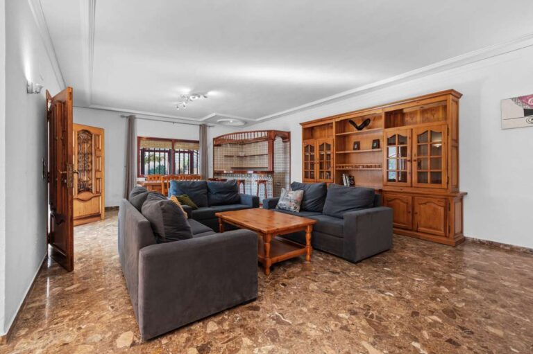 Living and dining room with wooden furniture and natural light inside a spacious villa in Calpe.