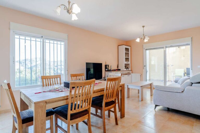 Living and dining space inside a semi-detached house in Calpe with sofa seating, dining table and large windows