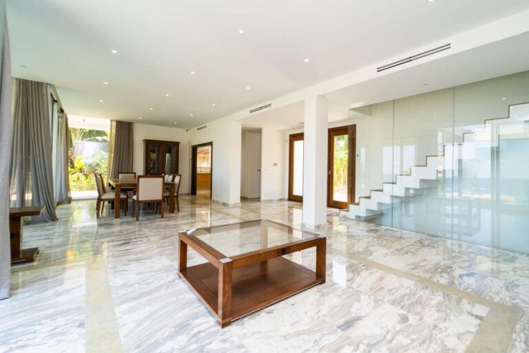 Living area inside a luxury villa in Calpe with marble flooring, glass staircase, open-plan layout and natural light