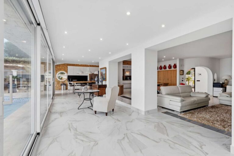 Living area inside a premium coastal villa on the Benissa Costa with terrace access, white sofa seating, modern dining area and bright open-plan design