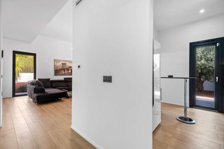 Living area inside a single-level modern villa in Santa Clara, Altea with terrace access, sofa seating, white walls and modern wood flooring