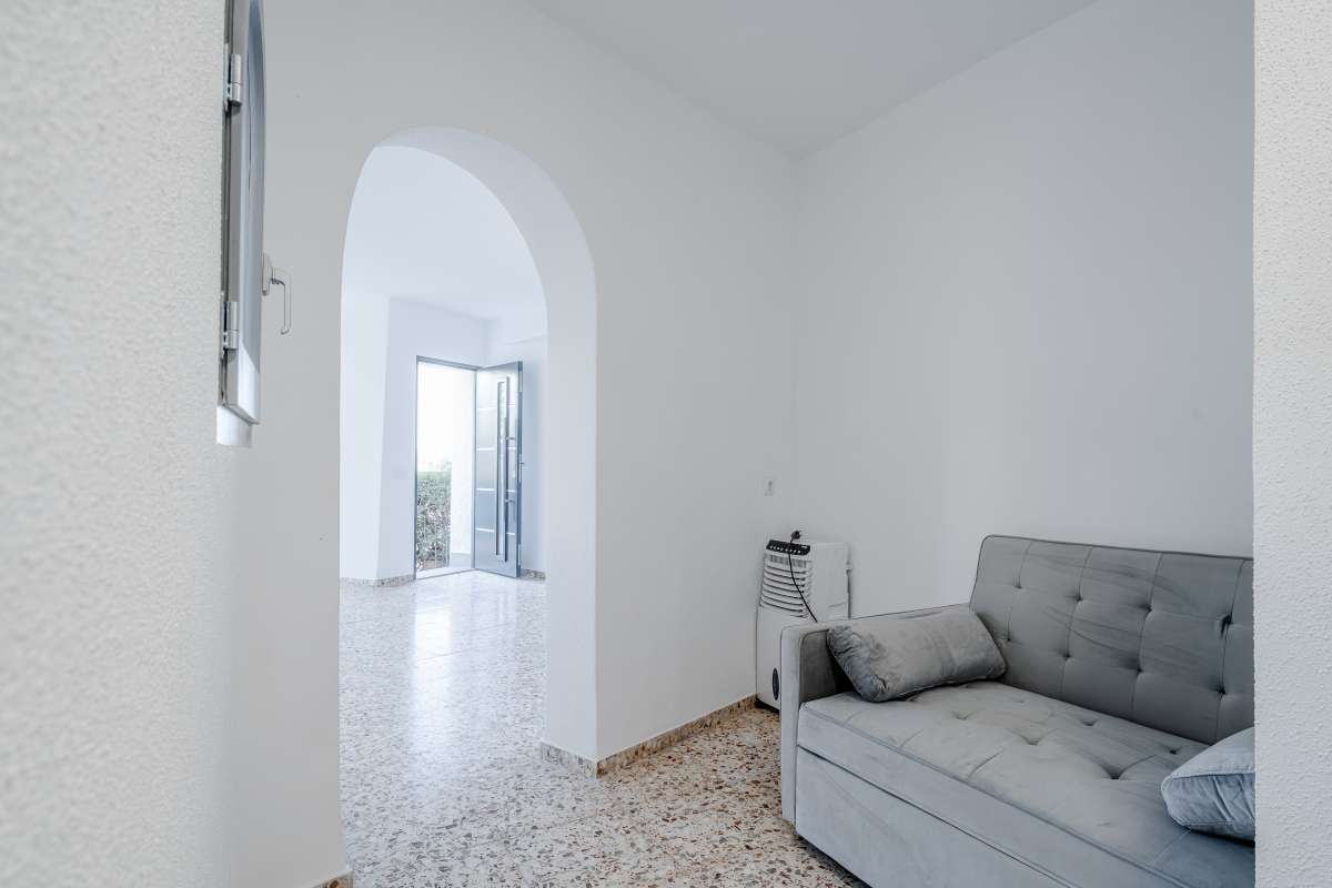 Living area with arched doorway, sofa and natural light inside an independent apartment at a Mediterranean villa in Maryvilla, Calpe.
