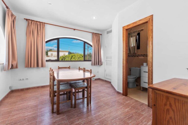 Living area with dining table, arched window and natural light inside a guest apartment at a spacious villa in Calpe.