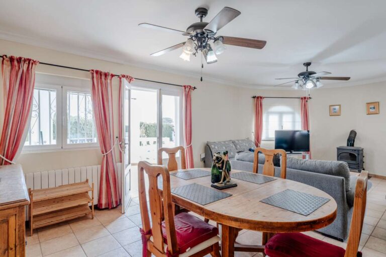 Living area with fireplace, dining table and natural light inside a Mediterranean villa with guest accommodation in Calpe.