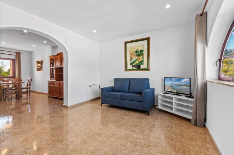 Living area with sofa, arched opening and natural light inside a guest apartment at a spacious villa in Calpe.